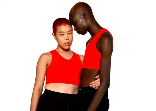 Two models in red half binders hold one another.